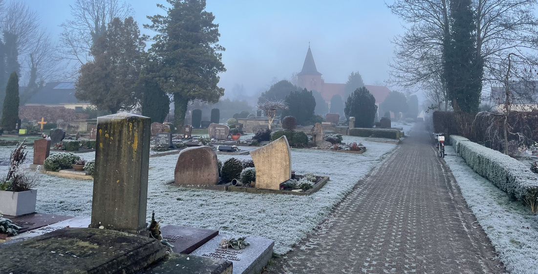 Andere Seite des Friedhofs bei Winter, die Kirche im Hintergrund