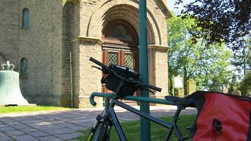 Zu sehen ist ein Fahrrad vor einer Kirchentür.