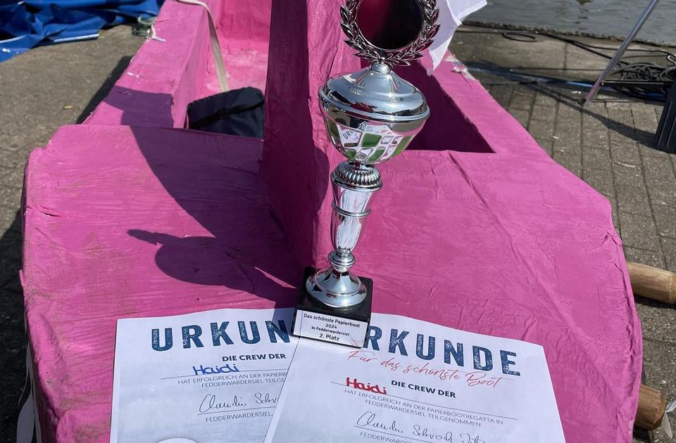 Zu sehen ist das Pappboot für die Pappbootregatta, mit dem Pokal für den zweiten Platz.