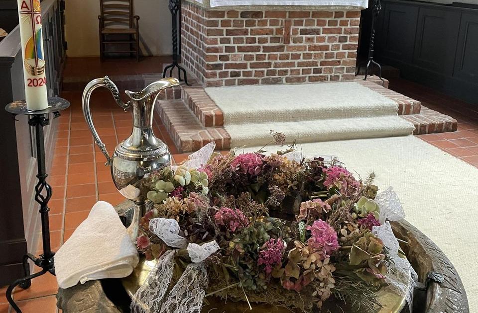 Im Vordergrund ist das Taufbecken der Kirche zu sehen, hinten der Altar.